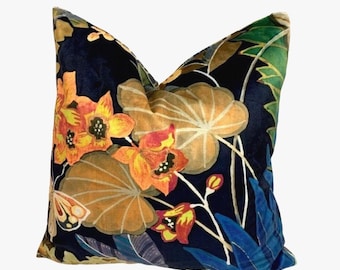 May include: Decorative throw pillow with a dark blue background and a floral pattern. The design features orange and yellow flowers, large tan leaves, and blue foliage. The pillow has a soft, textured appearance.