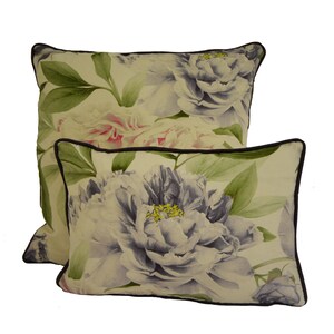 Puede incluir: Dos cojines decorativos con un dise&ntilde;o floral de peon&iacute;as. Los cojines presentan un fondo crema con grandes peon&iacute;as de estilo acuarela en tonos blancos, rosas y morados. Hojas verdes y un borde marr&oacute;n oscuro completan el dise&ntilde;o.