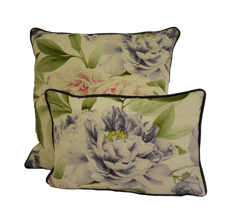 Puede incluir: Dos cojines decorativos con un dise&ntilde;o floral de peon&iacute;as. Los cojines presentan un fondo crema con grandes peon&iacute;as de estilo acuarela en tonos blancos, rosas y morados. Hojas verdes y un borde marr&oacute;n oscuro completan el dise&ntilde;o.