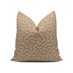 Pode incluir: Uma almofada decorativa com um padrão de coral branco e laranja.