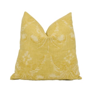Puede incluir: Una almohada amarilla con un patrón floral blanco.