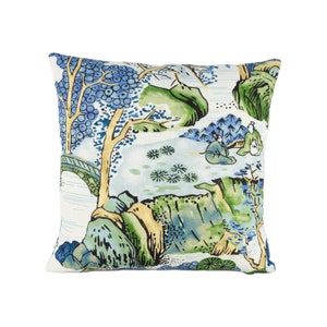 May include: A white throw pillow with a blue and green landscape design. The design features trees, mountains, and figures in traditional Chinese clothing.
