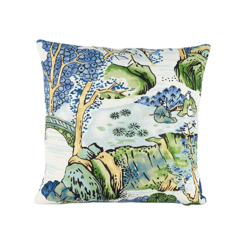 May include: A white throw pillow with a blue and green landscape design. The design features trees, mountains, and figures in traditional Chinese clothing.