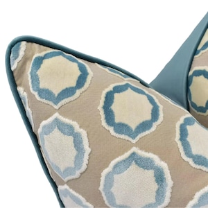 a close-up view of a decorative pillow with a repeating pattern of blue and beige geometric shapes.