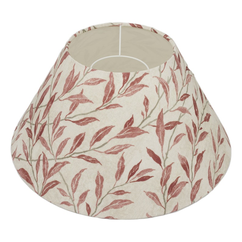 May include: A beige lampshade with a red leaf pattern. The lampshade is cone-shaped and has a white lining.