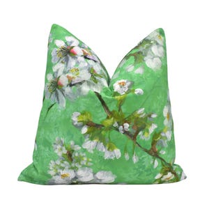 May include: A green pillow with a floral pattern of white flowers and green leaves. The pillow is made of a soft, comfortable fabric and has a zipper closure.
