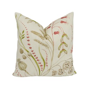 May include: A cream-colored pillow with a floral pattern featuring red, green, and brown botanical illustrations. The pillow has a subtle linen texture.