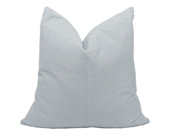 May include: A light blue throw pillow with white stripes. The pillow is made of a soft, textured fabric.
