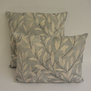 May include: Two decorative throw pillows with a light blue background and a white leaf pattern.
