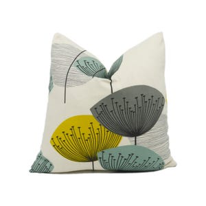 May include: A white pillow with a floral pattern in shades of yellow, gray, and blue. The pillow features a stylized dandelion design.