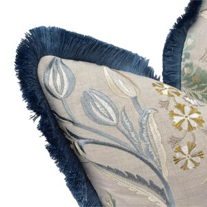 a close-up view of a decorative pillow with a floral pattern and a blue fringe trim.