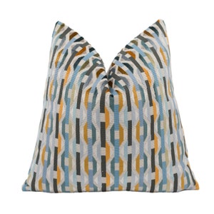 May include: A decorative throw pillow featuring a geometric pattern in shades of blue, gold, and grey.