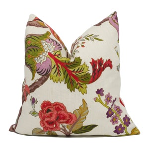 Puede incluir: Una almohada blanca con un patrón floral con flores y hojas rojas, rosas, verdes y moradas.