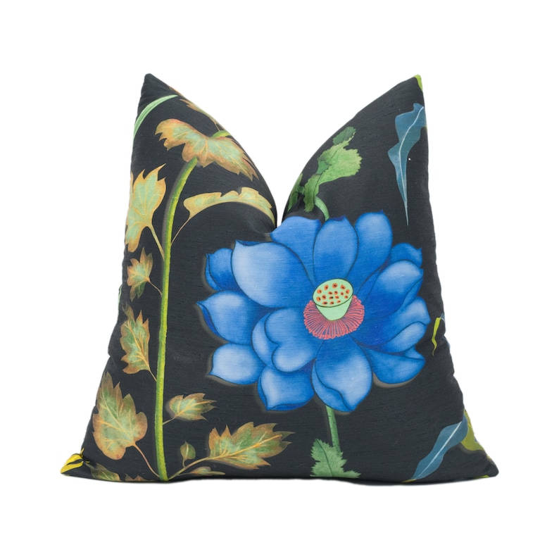 May include: A black pillow with a blue flower and green leaves printed on it. The flower has a red center and yellow accents.