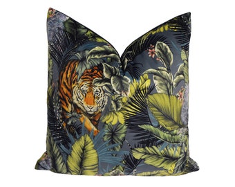 May include: A gray velvet pillow with a colorful jungle print featuring a tiger, palm leaves, and flowers.