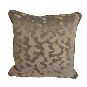 May include: A square cushion with a beige and brown abstract pattern. The cushion has a soft, plush texture.