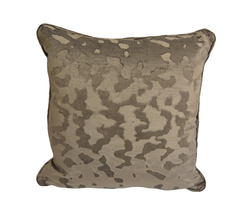 May include: A square cushion with a beige and brown abstract pattern. The cushion has a soft, plush texture.