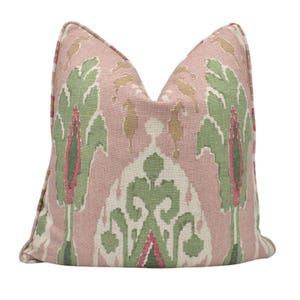 Puede incluir: Una almohada de tiro rosa y verde con un diseño ikat. La almohada está hecha de una tela suave y tejida.
