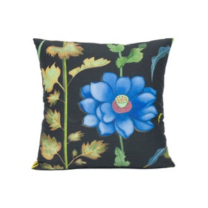 May include: A black pillow with a blue flower and green leaves printed on it.