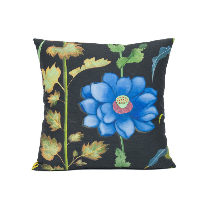 May include: A black pillow with a blue flower and green leaves printed on it.