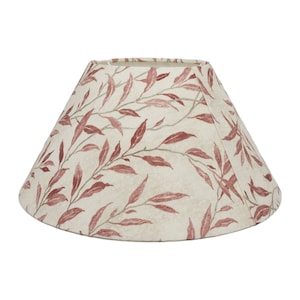 May include: A cream-colored lampshade with a red leaf pattern. The shade is a cone shape and has a scalloped edge.