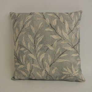 May include: A gray and white patterned throw pillow with a leaf design.