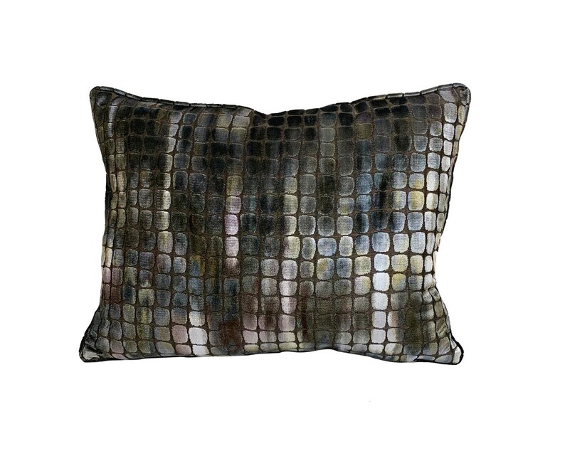 May include: A rectangular pillow with a geometric pattern in shades of brown, gray, and white. The pillow has a subtle sheen and a soft, plush texture.