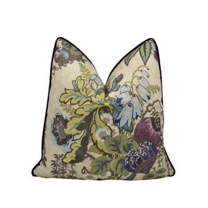 May include: Cushion featuring a floral design in green, blue, and purple hues on a cream backdrop. The pillow has a black trim and a botanical pattern, ideal for interior decoration.