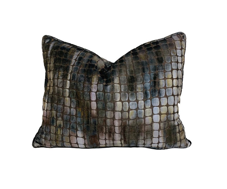 May include: A decorative pillow with a geometric pattern in shades of brown, green, and blue. The pillow has a square shape and a soft, plush texture.