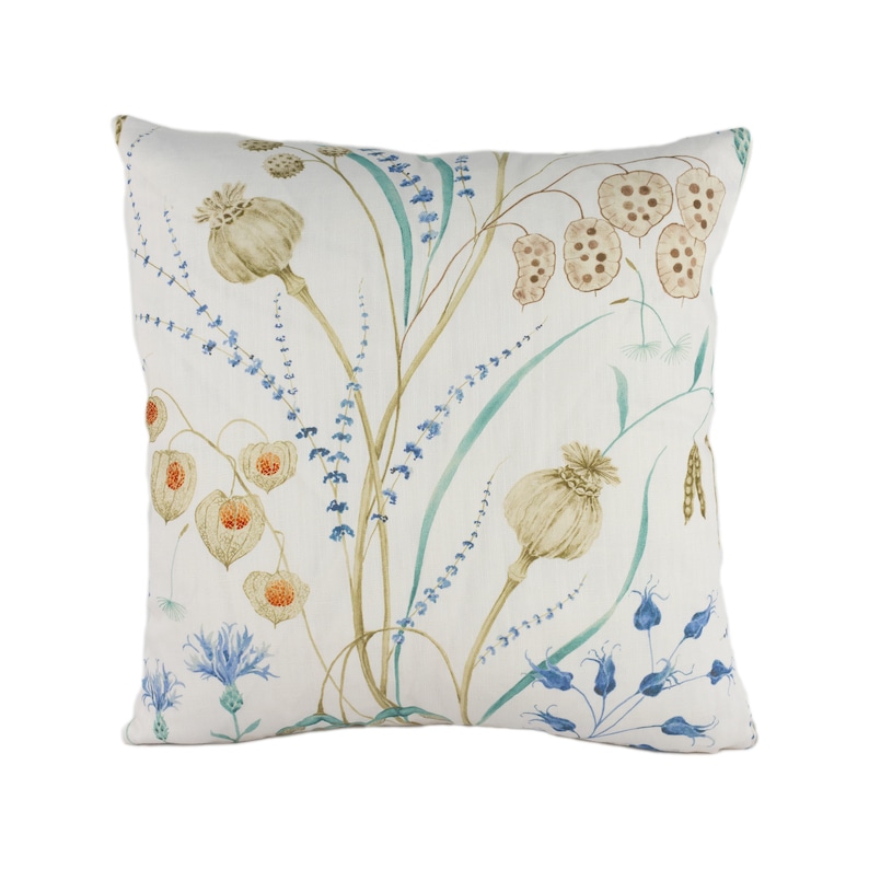 May include: A white throw pillow with a floral pattern featuring blue, green, and brown flowers. The pillow has a white background and a subtle linen texture.