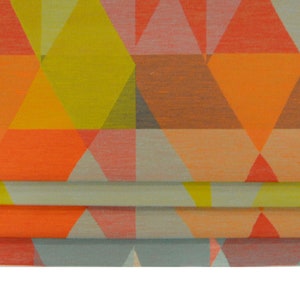 Può includere: Un tessuto con motivo geometrico con un motivo ripetitivo di triangoli in tonalità di arancione, giallo, rosa e grigio.