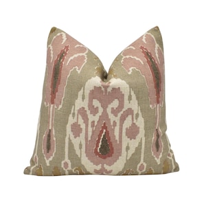 May include: A decorative throw pillow with a pink and brown ikat pattern on a beige background.
