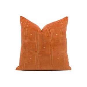 May include: A burnt orange throw pillow with a geometric pattern in a lighter shade of orange.