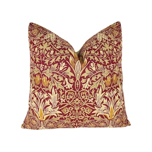 May include: A red and gold patterned throw pillow with a floral design. The pillow is made of a soft, comfortable fabric and is perfect for adding a touch of elegance to any room.
