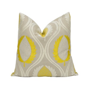 May include: A beige pillow with a yellow and white embroidered leaf pattern.