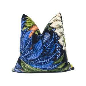 May include: A black pillow with a blue, green, and white floral pattern. The pillow is made of a soft, luxurious fabric and features a unique, eye-catching design.