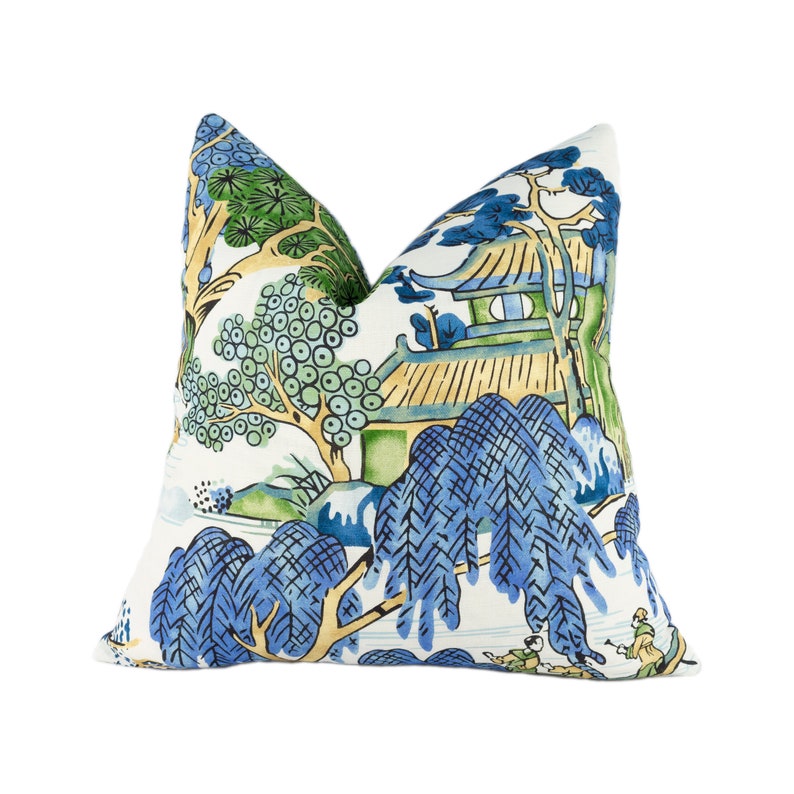 May include: A white pillow with a blue and green Chinese landscape design. The pillow features a pagoda, trees, and figures in a traditional style.