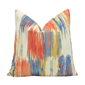 Pode incluir: Uma almofada decorativa com um padrão abstrato em tons de azul, laranja, vermelho e amarelo.