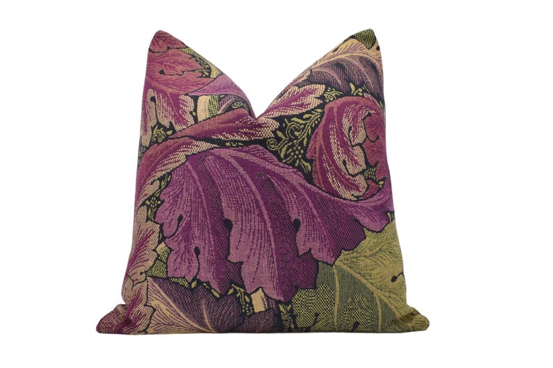 a purple and green floral pillow on a white background