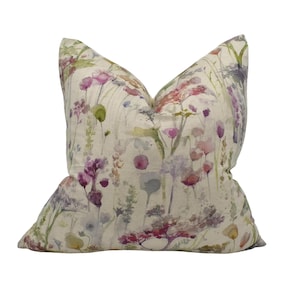 May include: A square throw pillow with a watercolor floral print featuring pink, purple, and green flowers on a cream background.