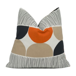 May include: A white pillow with a geometric pattern of black, orange, and beige semi-circles. The pattern is outlined in black lines.