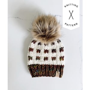May include: A hand-knitted winter hat with a faux fur pom-pom. The hat features a white crown with brown and green accents, and a brown and green brim. The text "KNITTING PATTERN" is in the upper right corner.