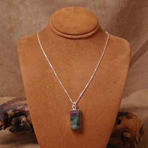 May include: A silver chain necklace with a rectangular green, pink, and white gemstone pendant.