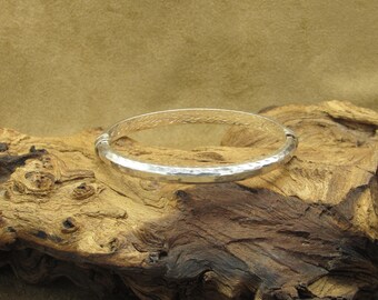 May include: A silver bangle bracelet with a hammered finish and a braided design around the edge.