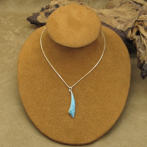 May include: A silver chain necklace with a turquoise pendant shaped like a teardrop. The pendant is set in silver and has a blue and green color.