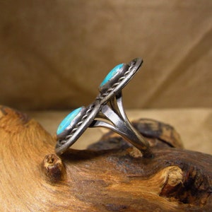 May include: A silver ring with two turquoise stones set in a twisted band.