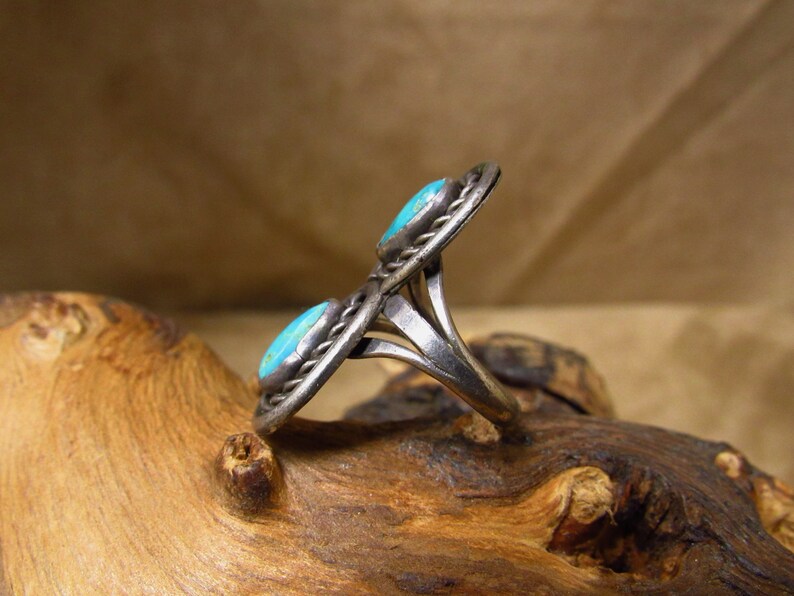 May include: A silver ring with two turquoise stones set in a twisted band.