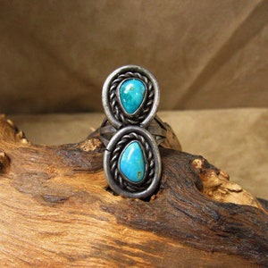 May include: A silver ring with two turquoise stones set in a twisted wire design.