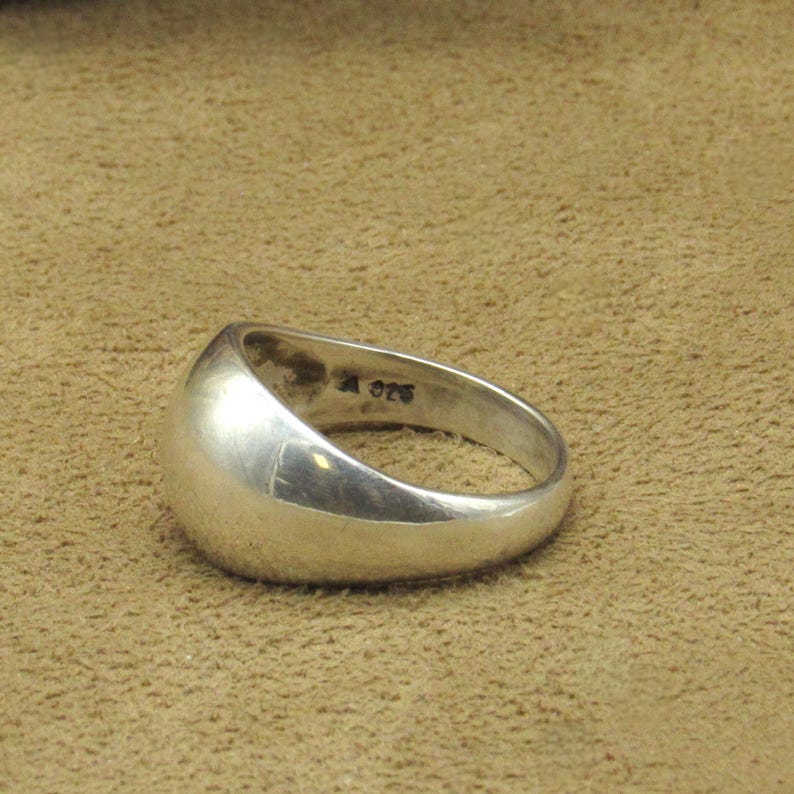 Peut inclure: Une bague en argent avec une surface arrondie et lisse. La bague a un design simple et classique. L'int&eacute;rieur de la bague est estampill&eacute; "A 925".