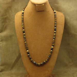 May include: A long necklace made of brown, black, and gold beads. The beads are round and have a smooth, polished finish.